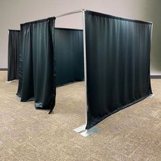 an empty room with two black curtains on the floor and one is closed up to reveal something