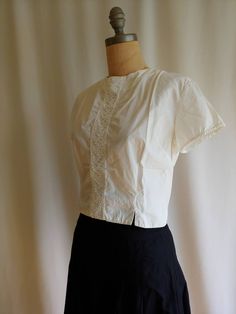 An iconic 50s 60s era blouse in a crisp pure white cotton Adorable high quality cut out lace inset in front Two front slits provide more movement Darts give this blouse ample bust roominess Shorter cropped style No label Bust - 20 inches Waist - 32 - 34 inches Back - 14 inches Length - 18 inches Excellent vintage condition Clean and ready to wear The pure cotton skirt it is photographed with can be found here: Vintage Fitted Tops With Broderie Anglaise, Fitted Classic Tops With Broderie Anglaise, Classic Cotton Lace Top Blouse, Classic Cotton Lace Top, Fitted Cropped Top With Lace Collar, Cropped Lace Trim Tops For Daywear, Vintage Cotton Blouse With Lace Top, Retro Cotton Top With Lace Collar, Retro Cotton Blouse With Lace Collar