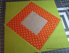 an orange and green patchwork quilt on a cutting board