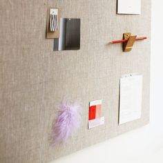 a bulletin board covered in magnets and paper with pink feathers on it's side