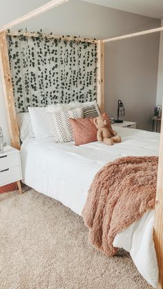 a teddy bear sitting on top of a bed in a room with white walls and carpet