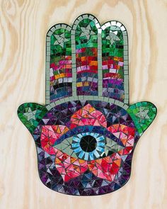 a mosaic hamsa with an eye on it's palm and stars in the middle