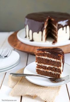 a slice of chocolate layer cake on a plate with a fork and knife next to it