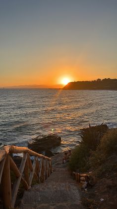 the sun is setting over the ocean and there are steps leading up to the beach