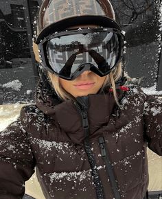 a woman standing in the snow wearing ski goggles