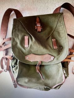 "These Vintage never issued / never used Romanian Military  Backpacks are made of thick canvas and even thicker leather put together with  heavy machine stitching and metal rivets. Bags are in unused Mint condition. They Are Roughly  40 Liters. INSIDE OF MAIN PACK: Cord Closure   Dimensions from seam to seam roughly measure 11 3/4\" To 13 3/4\" x 15 5/8\" x 10 1/4\"  these packs are wider on the bottom than on the top. The main pack space is covered by a large flap with buckle closure . EXTERNAL OF BACKPACK FEATURES: The main cover / flap  has leather attachment points I am assuming it was used  for a mess kit. On the sides you'll find additional  attachment points for a bed roll etc. and on the other side of pack  there is a  pouch for Rations or a Canteen etc.. Pack does not come with he Vintage Canvas Satchel For Outdoor, Vintage Leather Satchel Backpack For Outdoor, Vintage Backpack For Outdoor Activities, Vintage Waxed Finish Backpack, Vintage Backpack With Leather Handles, Vintage Canvas Backpack For Outdoors, Vintage Canvas Satchel Backpack, Military Style Backpack For Adventure, Vintage Backpack With Leather Handles For Outdoor