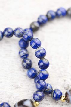 This traditional and bold Dzi bead wrist mala looks amazing on both men and women. Hand strung in Michigan and exclusive to the DharmaShop! Powerful, high-quality, and top grade Lapis beads surround a true agate Dzi bead centerpiece from Taiwan with two gold plated spacers from Thailand. The Dzi bead features a Tiger Tooth design known to energize the wearer as well as attract good luck and health. Tiger Teeth Dzi can assist the owner with concentration, determination, and completion. It is also Third Eye Chakra Stones, Tiger Tooth, Wrist Mala, Third Eye Chakra, Chakra Stones, Taiwan, Agate, Gold Plate, Beaded Bracelets