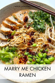 a white bowl filled with noodles, meat and veggies next to chopsticks