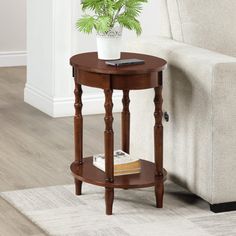 a small table with a potted plant on it in front of a white couch