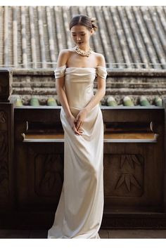 a woman in a white dress is sitting on a bench