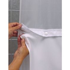 two hands are opening the back of a shower curtain to show it's white fabric