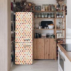 a kitchen with an old fashioned refrigerator in the center and shelves full of jars on the wall