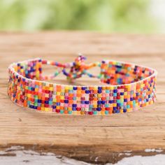 a multicolored beaded bracelet sitting on top of a wooden table