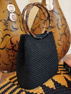 a black purse sitting on top of a table next to two vases and a rug