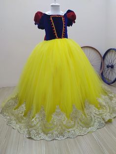 a yellow dress with red and blue trims is on display in front of a white wall