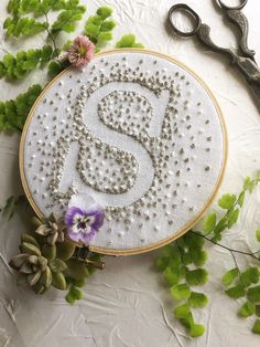 an embroidered monogram with the letter s on it next to some flowers and scissors