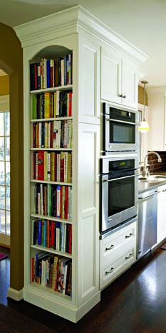 a kitchen with an oven, microwave and bookcase