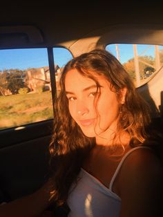 a woman sitting in the back seat of a car with her head out the window