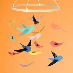 there is a bird mobile hanging from the ceiling in front of an orange wall with birds on it