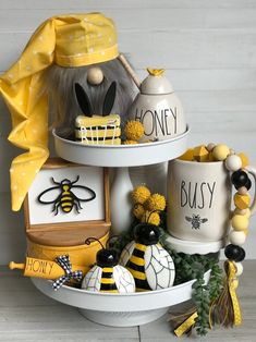 three tiered trays with bee themed items on them, one is yellow and the other is white