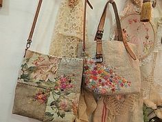 several purses are hanging on the wall with lace and flowery fabric around them