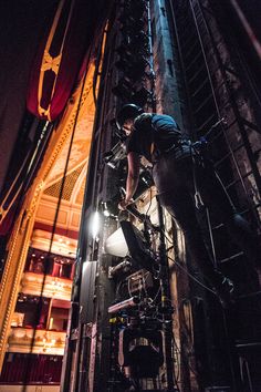 a man standing on top of a metal structure next to a light fixture in a dark room