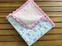 two baby blankets sitting on top of a wooden table