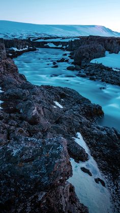 the water is blue and green as it sits on some rocks