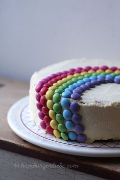 a cake with white frosting and multicolored icing on a wooden table