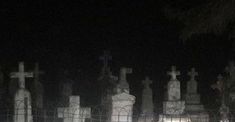 a cemetery at night with many headstones and crosses