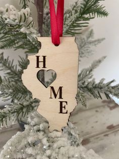 a wooden ornament that says home with a heart in the shape of a state