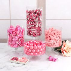 pink and white candies in glass vases on marble counter