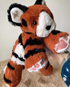 a hand holding a stuffed animal that looks like a tiger