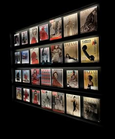 a man standing in front of a wall covered with magazine covers and magazines on display