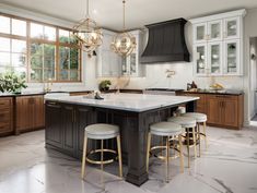 a large kitchen with marble counter tops and wooden cabinets, along with bar stools