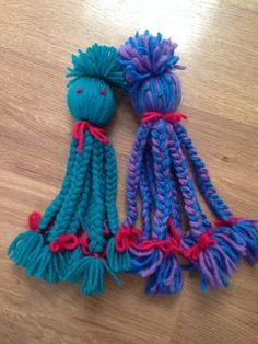 two blue and purple knitted dolls sitting on top of a wooden table