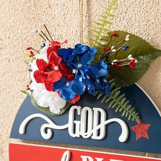 a blue sign with red, white and blue flowers sitting on top of it's side