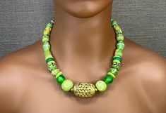 This 20" necklace feels like the green grass of an African summer. It is designed with various handmade Ghana glass beads in shades of green with a large 'basket weave' brass focal bead from Côte d'Ivoire. It has a large brass lobster cloth glass with extension chain for ease of use and positioning on the neck. These beads are all handmade in Africa by crafts people who have been creating these beads for centuries. This creates a sustainable business for many African families using a completely recycled green product. The organic feel of these beads creates a beautiful piece of one of a kind, wanderlust jewelry. This necklace can be paired with many styles of clothing and is perfect for both day and evening wear. It makes a wonderful gift for the woman who Likes to collect unique jewelry p Traditional Green Adjustable Necklace, Unique Green Adjustable Necklace, Traditional Green Beaded Necklace With Large Beads, Adjustable Green Beaded Necklace, Unique Green Necklace With Polished Beads, Green Glass Jewelry With Colorful Beads, Spiritual Green Necklaces With Colorful Beads, Traditional Green Spacer Beads, Green Glass Beaded Necklaces For Jewelry Making