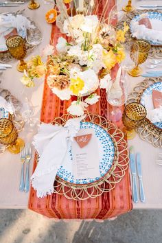 the table is set with plates, silverware and flowers