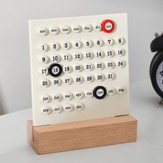 an alarm clock sitting on top of a table next to a wooden block with numbers