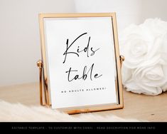 there is a sign that says kids table with flowers on the table next to it