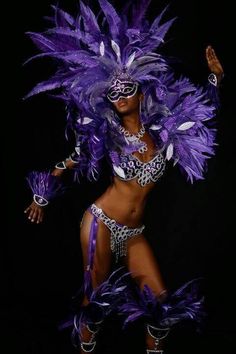 a woman in a purple costume with feathers on her head and hands behind her back