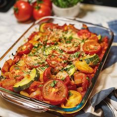 a casserole dish with tomatoes, zucchini and other veggies