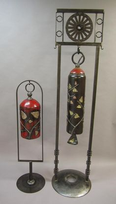 three metal objects are on display in front of a white background and one has a red fire extinguisher next to it