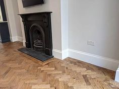 an empty living room with wood flooring and a tv mounted on the fireplace mantel