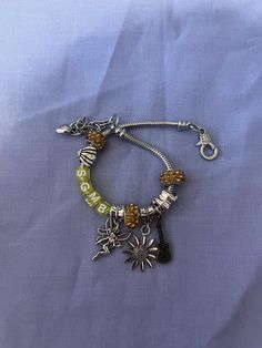 a bracelet with charms on it sitting on top of a blue cloth covered tablecloth