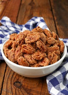 a white bowl filled with pecans on top of a blue and white checkered napkin