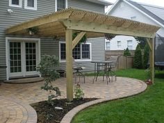 an outdoor patio with brick pavers and wooden pergol