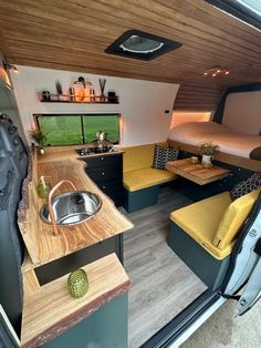 an interior view of a camper van with wood flooring and yellow cushions on the couches