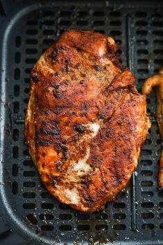 two pieces of meat sitting on top of a grill grate with chicken legs in it